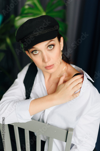 Portrait of a beautiful young woman in a white shirt and black trousers at home