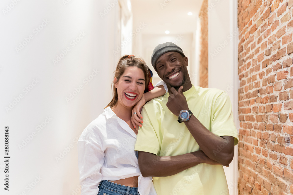 Happy interracial friends looking to camera against white corridor Happy interracial friends looking to camera against white corridor