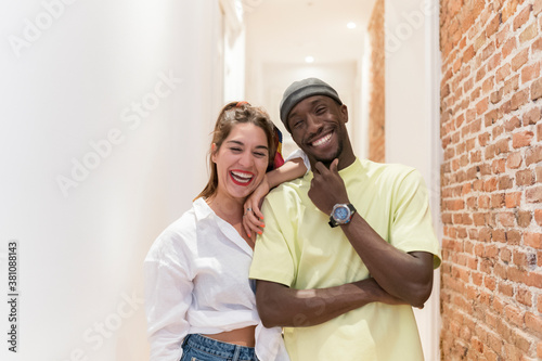 Happy interracial friends looking to camera against white corridor © Mikel Taboada