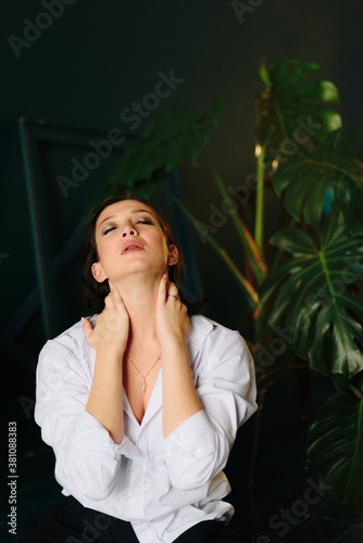 Portrait of a beautiful young woman in a white shirt and black trousers at home