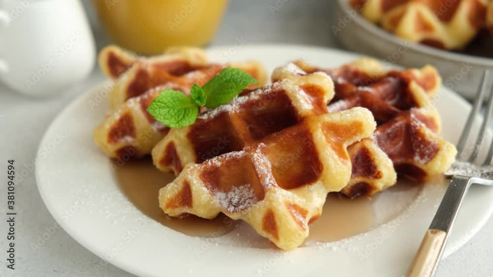 Belgian waffles with syrup and mint leaf on a plate. Sweet breakfast food Belgian waffles with syrup and mint leaf on a plate. Sweet breakfast food