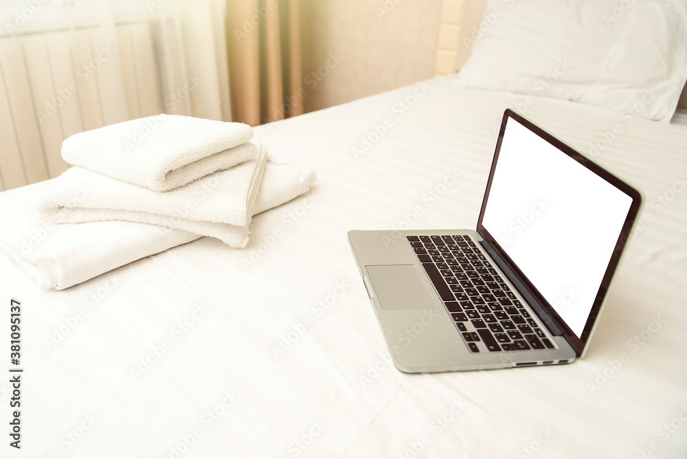 Laptop on the hotel bed with white towels Laptop on the hotel bed with white towels