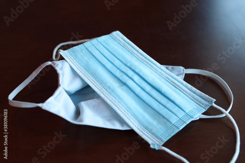 Protective mask on the wooden table General 3 layers mask to cover mouth and nose. (Concept of prevention of respiratory infections) surgical mask with ear band. COVID 19
