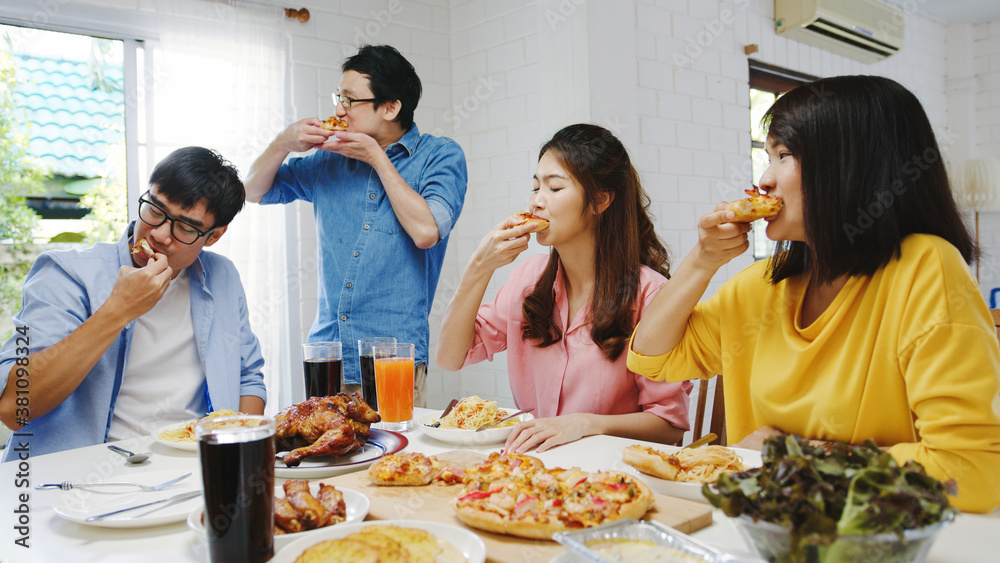 Happy young friends group having lunch at home. Asia family party eating pizza food and laughing enjoying meal while sitting at dining table together at house. Celebration holiday and togetherness. Happy young friends group having lunch at home. Asia family party eating pizza food and laughing enjoying meal while sitting at dining table together at house. Celebration holiday and togetherness.