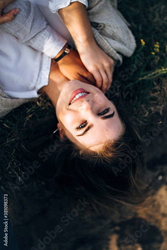 Close-up portrait of a beautiful girl lying on the ground. Man's hand touches the girl. Hand in hand. Hold hands