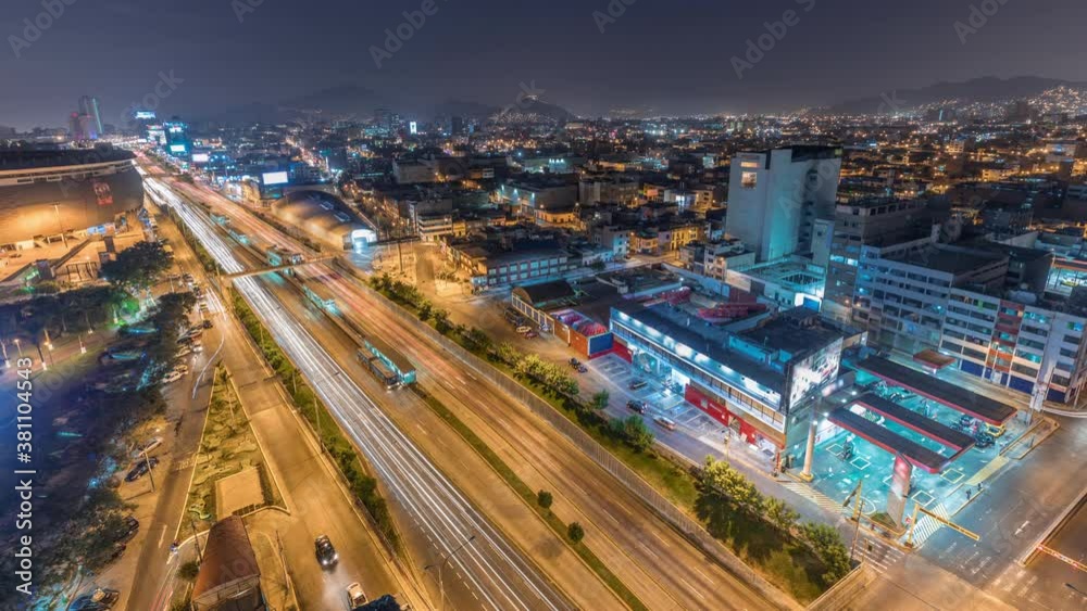 Aerial top view of Via Expresa highway and metropolitan bus with traffic day to night transition timelapse near National Stadium of Peru. Illuminated houses and city skyline with mountains on a Aerial top view of Via Expresa highway and metropolitan bus with traffic day to night transition timelapse near National Stadium of Peru. Illuminated houses and city skyline with mountains on a