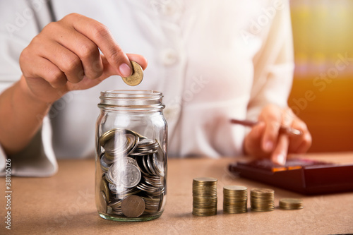 Woman hand putting money coin for saving money. Saving money for future plan and retirement fund concept.