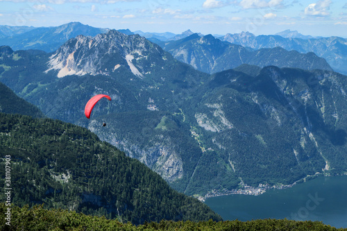 The paraglides are flying above the mountains high in the blue sky and enjoying the view.  photo