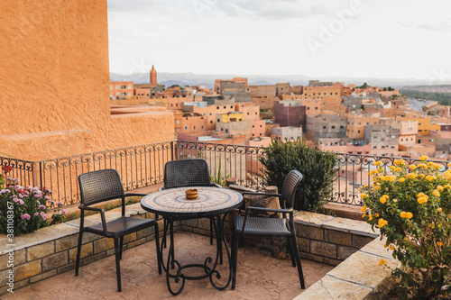 Restaurant table on terrace with amazing view of old arabic town Boumalne in Morocco at sunset. Three chair and ashtray.