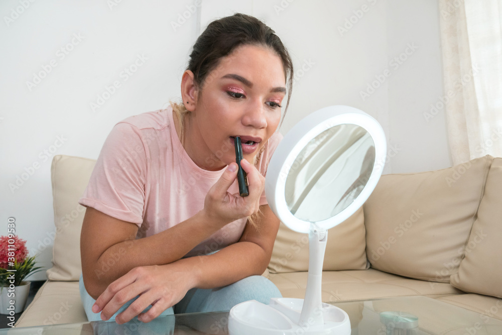 Woman applying lipstick in front of mirror Woman applying lipstick in front of mirror