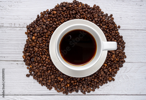 Arabika coffee beans and coffee cup on white wood background. Top view of Roasted Beans. copy space. food and drink concept.