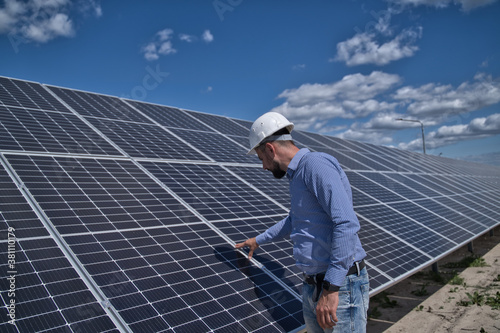 An engineer checks the solar panels. The management is checking the operation of the solar station.