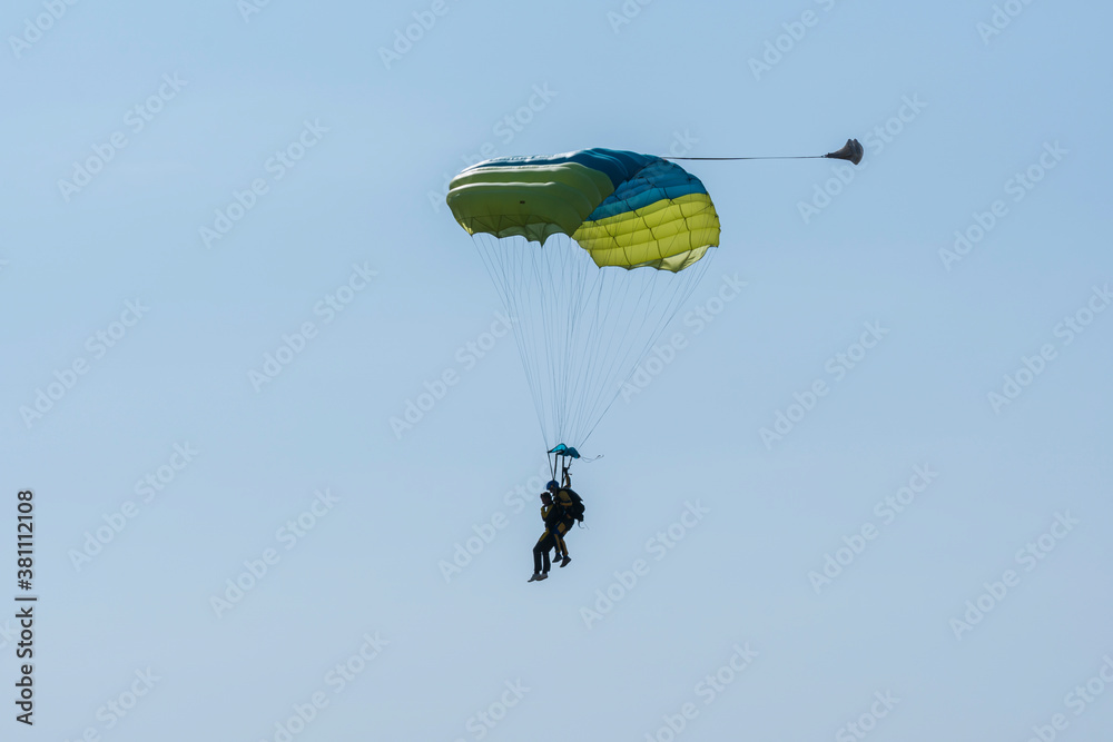 Tandem parachute jump. Silhouette of skydiver flying in blue clear sky. Concepts of extreme sport and adrenaline. Tandem parachute jump. Silhouette of skydiver flying in blue clear sky. Concepts of extreme sport and adrenaline.