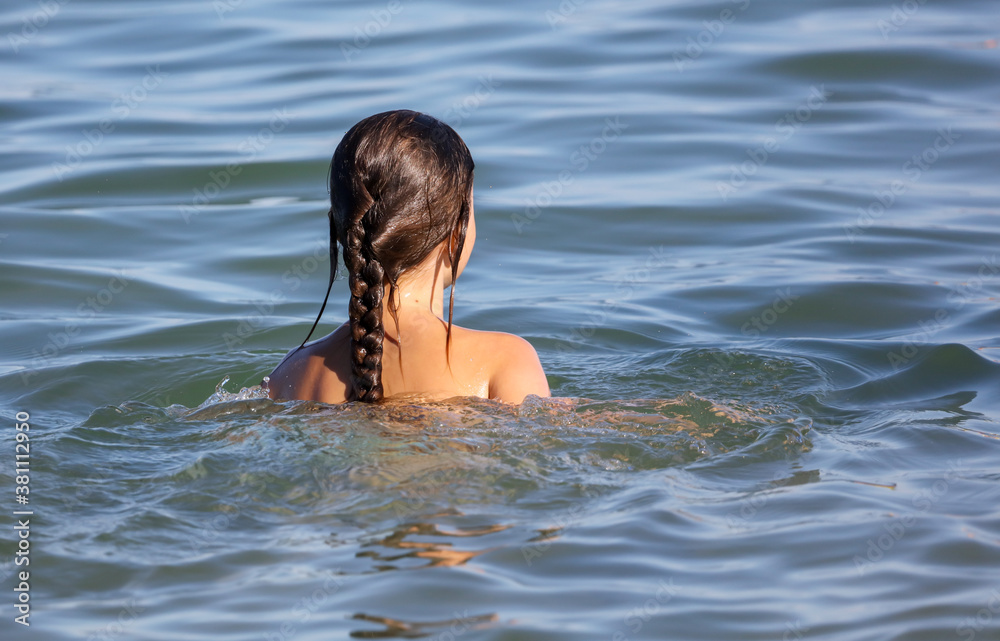 The girl swims in the water of the sea.