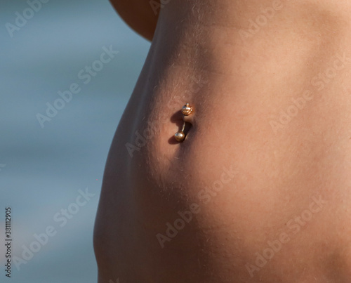 Belly button piercing of a girl in a bikini.