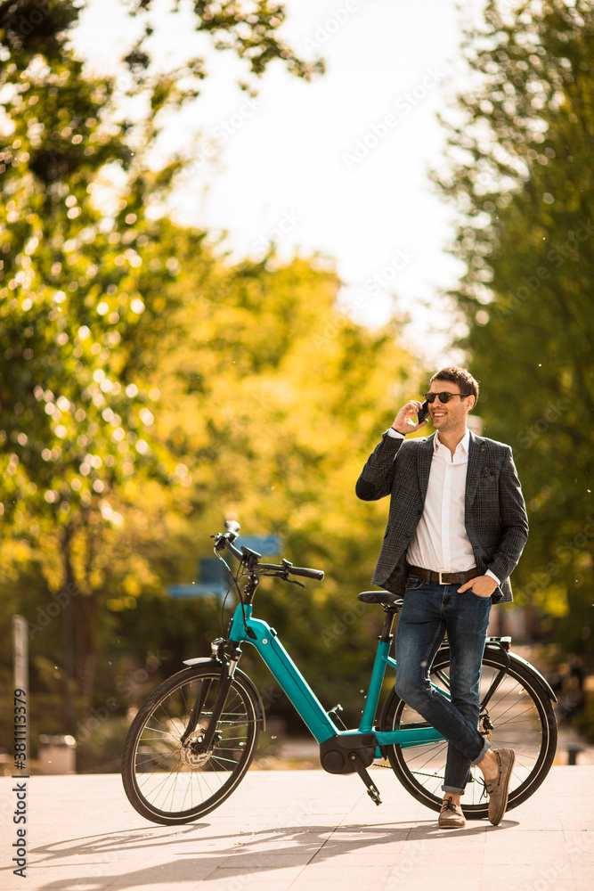 Obraz premium Young businessman on the ebike using mobile phone