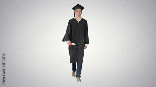 Smiling male student in graduation robe walking with his diploma