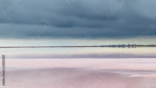 Salt pink lake reflective mirror water surface with vivid blue dramatic layered epic clouds on sky. Panoramic spa healthcare natural resort in Ukraine, Henichesk