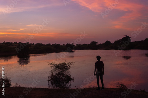 Silhouette of an Indian man standing in front of the lake during the sunset