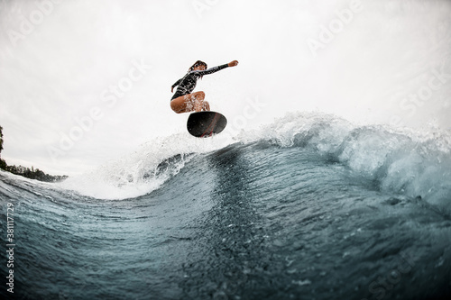 young active woman surfs coolly on surf board and jumps on the wave photo