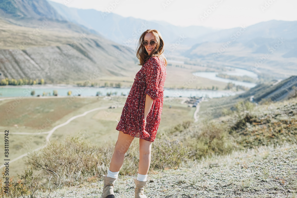 Young brunette woman in red dress on background of the turquoise Katun river, Altai mountains