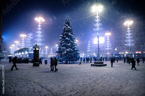 Zagreb main square at night with blue lightened christmas trees during snow storm, Croatia