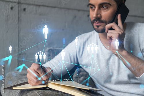 Handsome PR manager in casual wears, speaking phone, taking notes at office try to solve recruitment chalenge from customer. Double exposure. The concept of worldwide hiering in any industry. photo