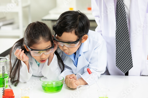 child student doing or testing a chemical experiment with science teacher by them side in laboratory classroom