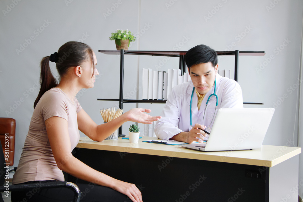 Young Asian male psychiatrist is specialist in psychiatry Caucasain female Patient serious together for therapy and talking for encourage with laptop in Clinical treatment for emotional symptoms. Young Asian male psychiatrist is specialist in psychiatry Caucasain female Patient serious together for therapy and talking for encourage with laptop in Clinical treatment for emotional symptoms.