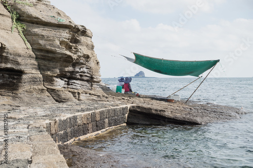 Local women selling fresh seafood sitting under a cover at Yongmeori Beach, Sanbang-ro, Jeju Island, South Korea photo