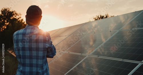 Owner looks at solar power plant panels at sunset