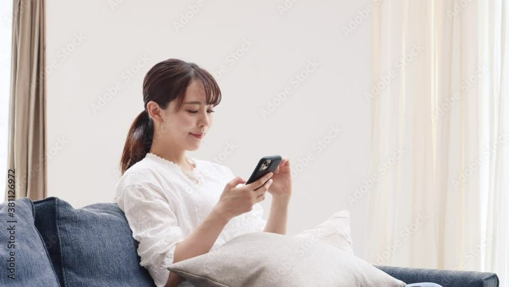 ソファーでスマートフォンを使う女性