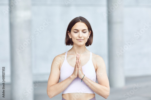Free Download Frau/Mädchen in Pastell gekleidet macht Outdoor Yoga Übungen/Sonnegruß/Gebet in moderner Beton Architektur. Urbanes Leben.  - GFXLoad