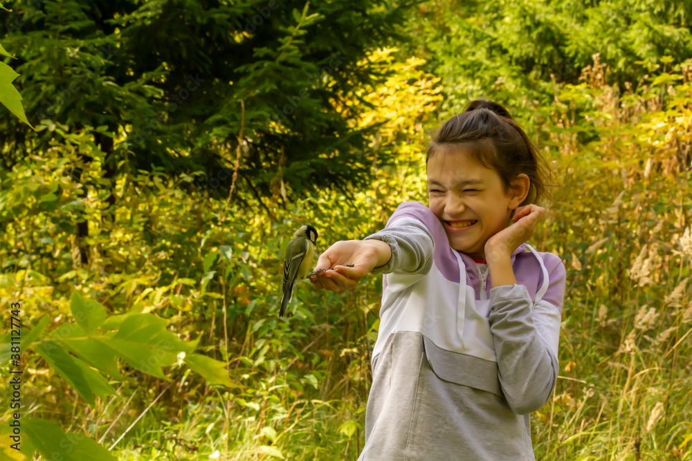 Laughing girl feeding birds in autumn forest. The concept of spending a joint family weekend in nature. Laughing girl feeding birds in autumn forest. The concept of spending a joint family weekend in nature.