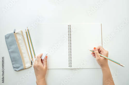 Top view of female's hand writing on a notebook paper with pencil