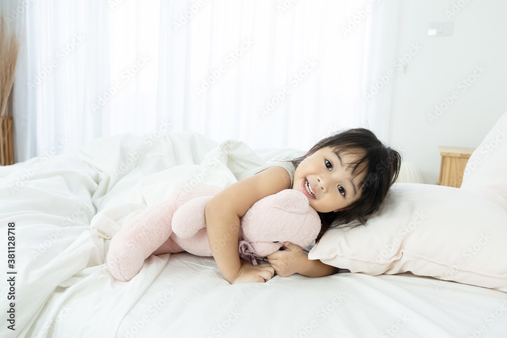 Adorable happy Asian toddler girl just wake up and still lie in bed with smiling face, happiness moment.. Adorable happy Asian toddler girl just wake up and still lie in bed with smiling face, happiness moment..
