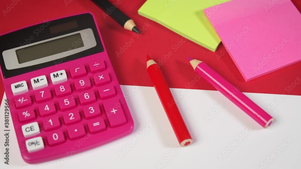 white paper and calculator and crayons on a red desk