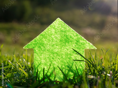 Eco house on fresh green grass in the sun. Investment, finance, mortgage concept.
