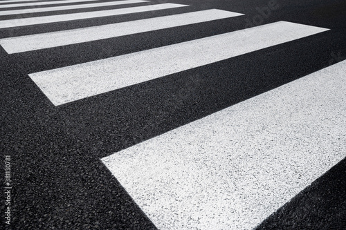 Particular pedestrian crossing, asphalt road, white stripes on a dark gray background, zebra stripes, perspective views, black and white.
