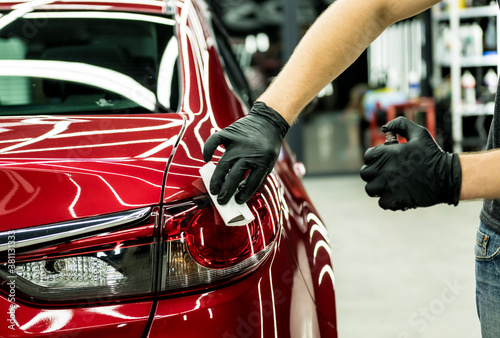 Car service worker applying nano coating on a car detail. © romaset