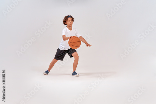 Favourite sport. Full-length shot of a teenage boy playing basketball while standing isolated over grey background, studio shot
