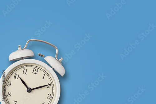 White vintage alarm clock on a blue background. Urgency, deadline and running out of time concept
