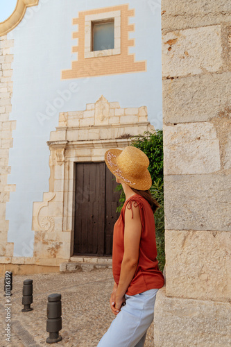 Brunette girl near the facade of a large old brick building in the old town. Walk in downtown. Portrait of a pretty girl on the street of the town