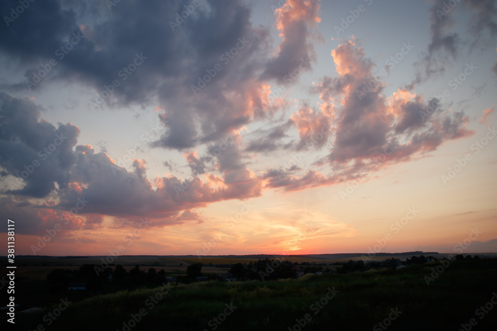 The morning sun and the orange sky. The beam of the sun hitting trees and flowers of grass.