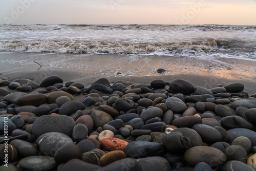 Pebbles on beach washed by waves at stormy weather