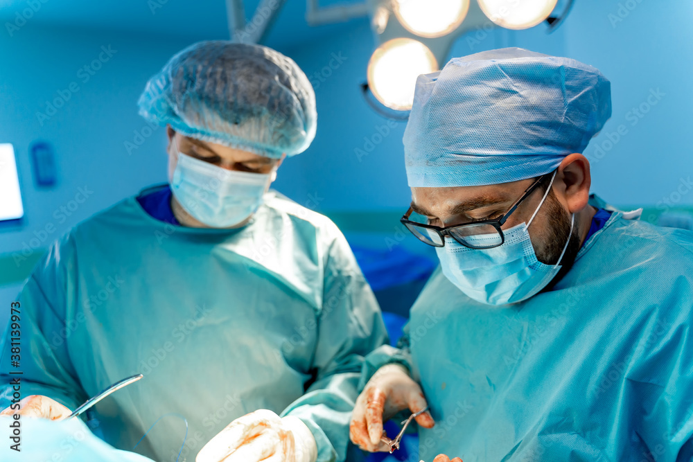 Surgeons working in operating room. Hospital background. Two male doctors at work. Medics in