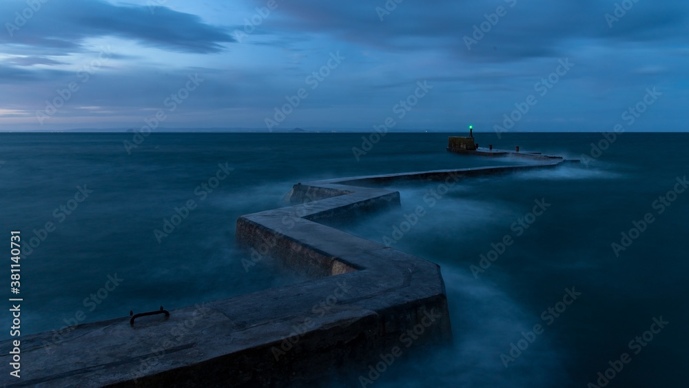 Obraz premium Waves in the sell around St Monans zigzag breakwater as the sun begins to rise.