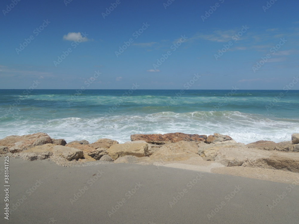 Seashore, turquoise sea, white waves, blue sky, sand and stones. Seashore, turquoise sea, white waves, blue sky, sand and stones.