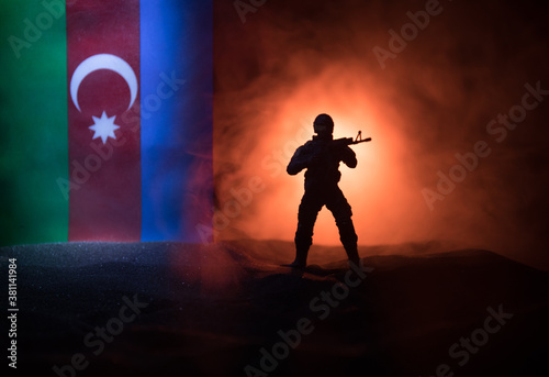 Azeri army concept. Silhouette of armed soldiers against Azerbaijani flag. Creative artwork decoration. Military silhouettes fighting scene dark toned foggy background.