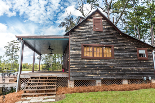 Scenic side view of the exterior of a rural rustic wooden camp house used for fishing and hunting. The house is located on a large pond